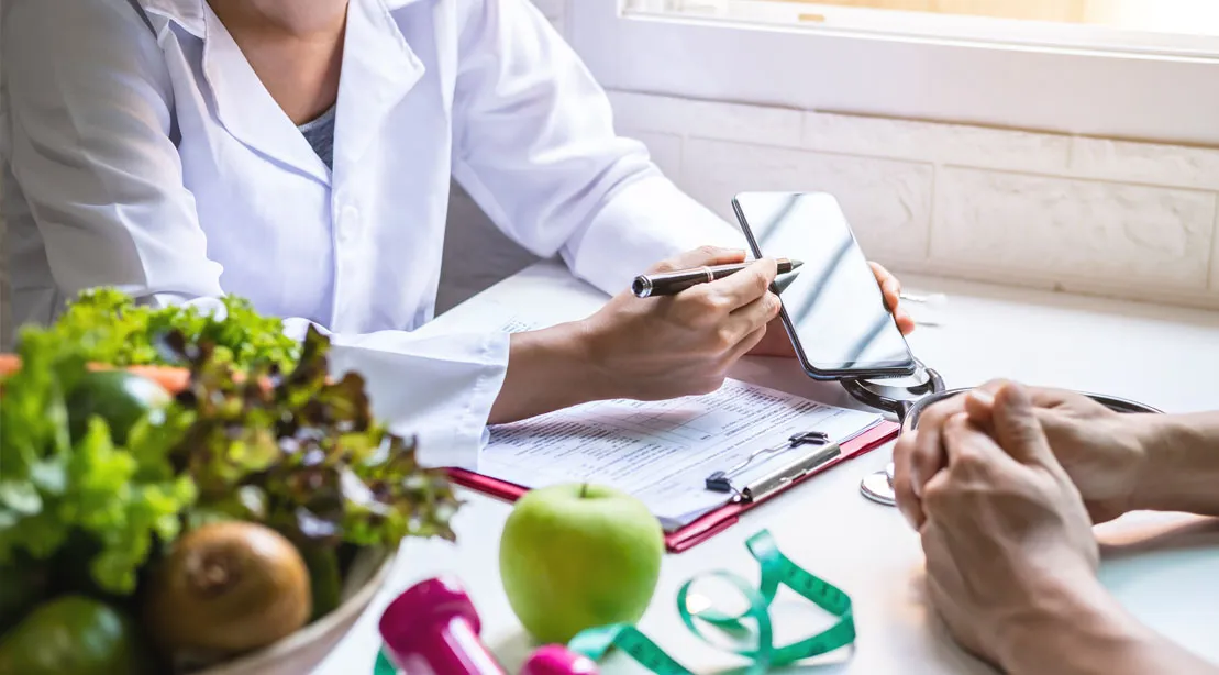 Doctor consulting a patient about nutritional health using a smartphone and medical report, with fruits and vegetables on the table.