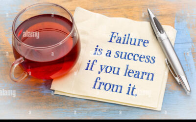 A cup of tea beside a napkin with the motivational quote 'Failure is a success if you learn from it' written on it."