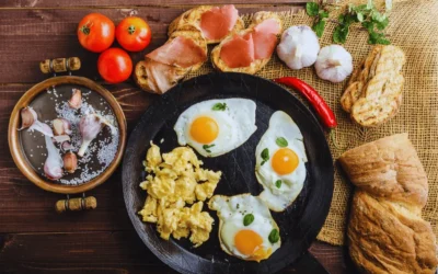 Top 10 High-Protein Snacks for Energy and Weight Management Fried and scrambled eggs with toasted bread, garlic, tomatoes, and herbs on a rustic wooden table a healthy high protein breakfast.