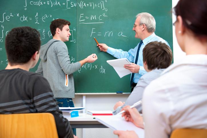 Teacher explaining physics equations to students in classroom