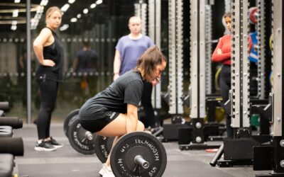How to Start Your Fitness Journey Young woman performing a deadlift in a gym under supervision