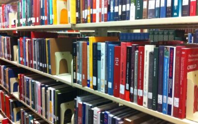 Collection Development in University Libraries: A Strategic Approach Rows of colorful books neatly arranged on library shelves with metal bookends.