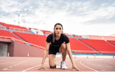 Best Fitness Tips for Young Athletes to Improve Performance Young female athlete preparing to sprint on outdoor running track at stadium