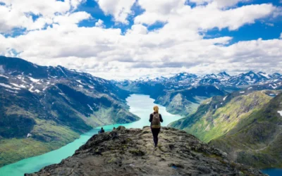 Adventure Travel Destinations: Explore the Thrill of the World in 2025 Hiker standing on a mountain summit overlooking rugged terrain—perfect for adventure travel content