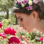 Woman enjoying the beauty of red roses in a flower garden.
