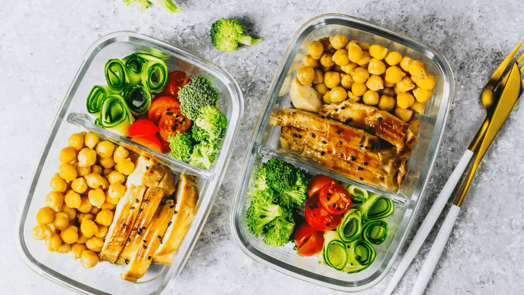 Healthy meal prep ideas featuring grilled chicken, chickpeas, broccoli, zucchini, and cherry tomatoes in glass containers.